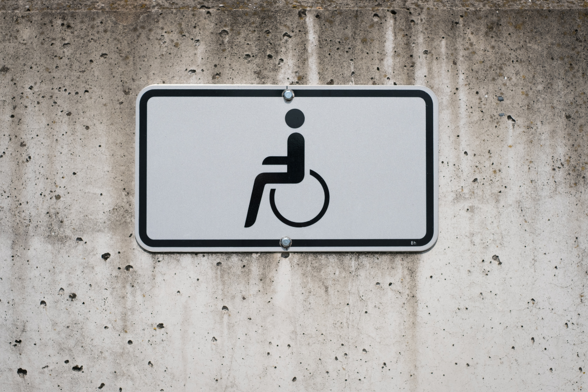 Black on white wheelchair symbol sign mounted on a cement wal