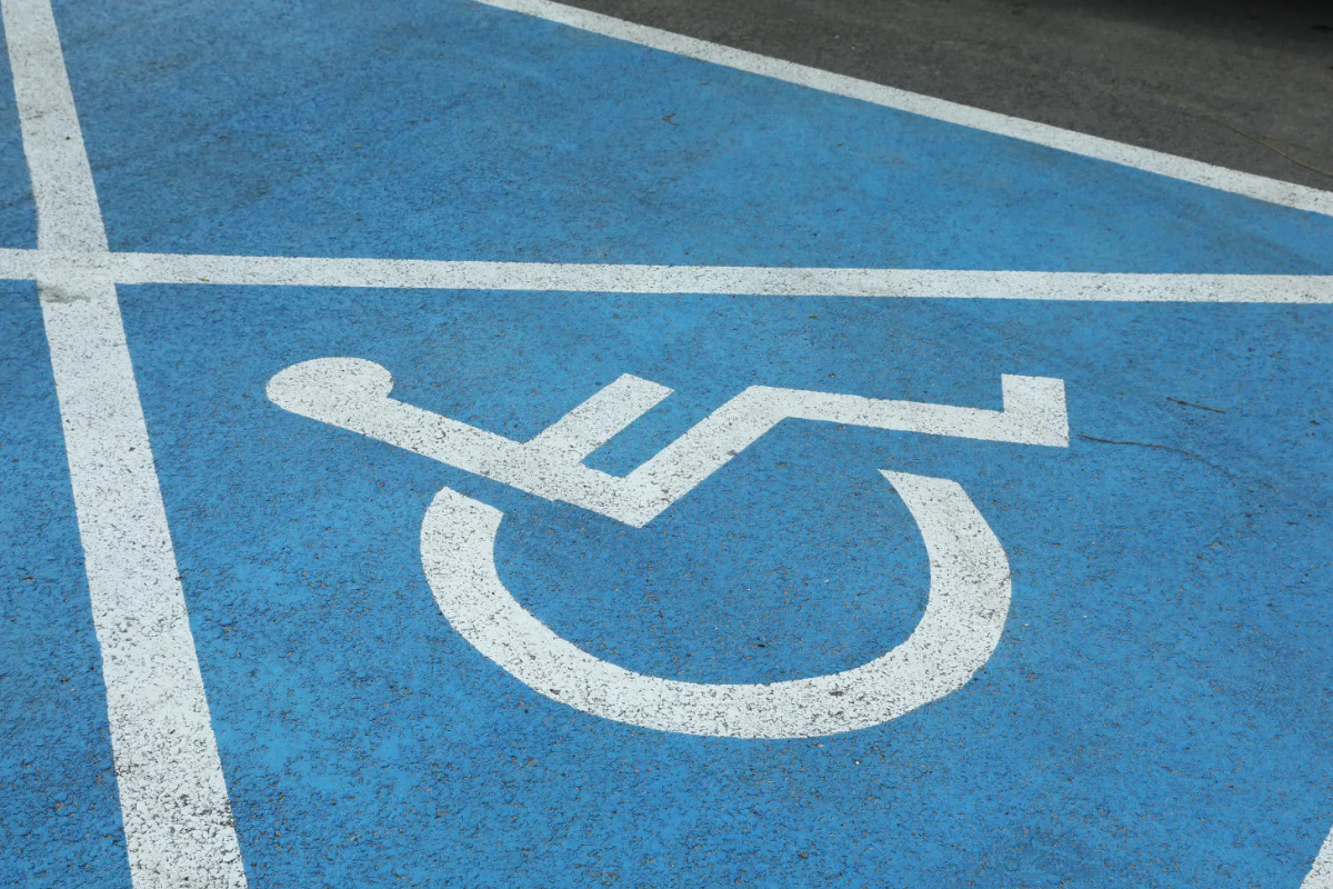 White wheelchair symbol and lines, on blue background, marking pavement of an accessible parking space