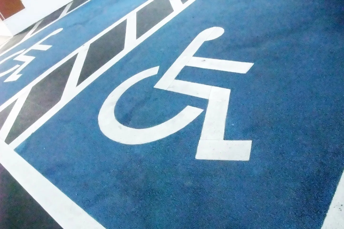 Angled closup of white on blue wheelchair symbols marking pavement of two accessible parking spaces