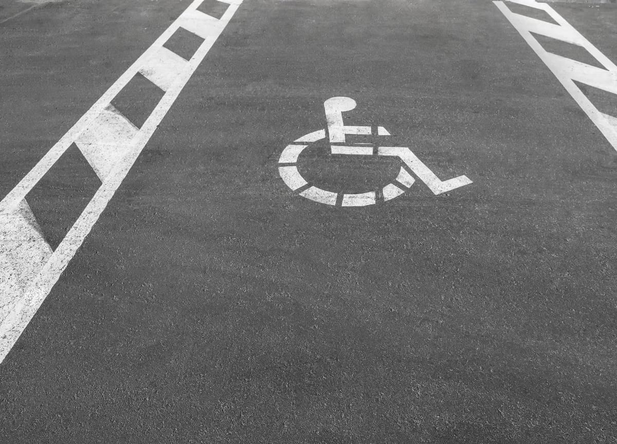 White stenciled wheelchair symbol and lines marking accessible parking space