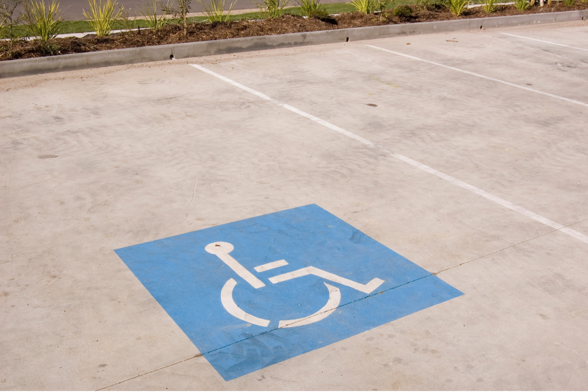 White on blue square wheelchair symbol painted on grey pavement