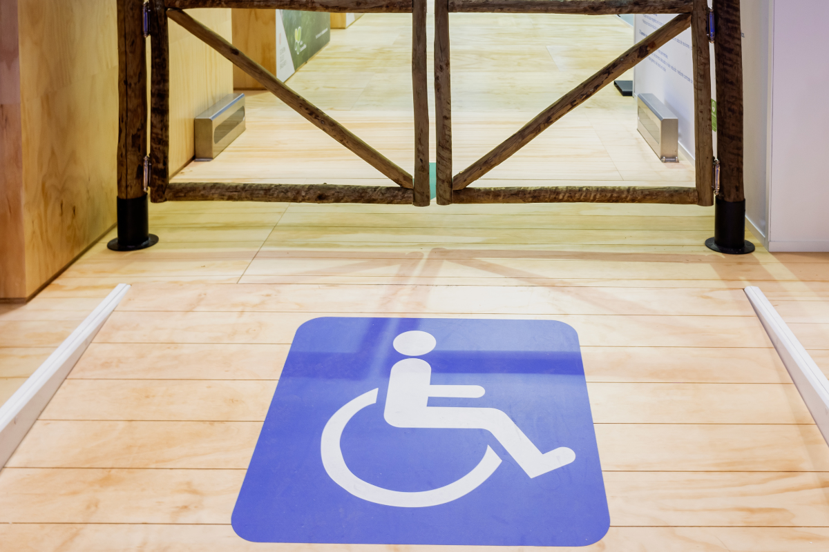 White on blue wheelchair symbol on the floor of a ramp leading to an exit gateway