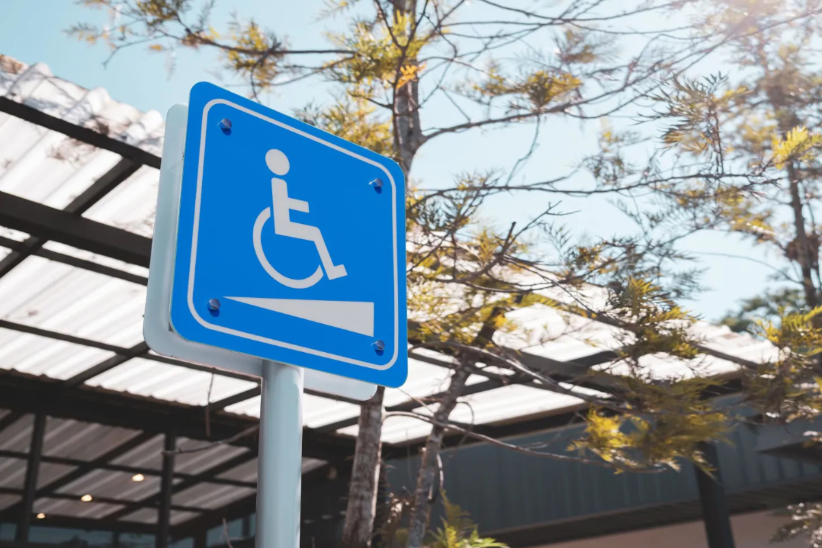 White on blue wheelchair ramp symbol on a vertical sign in front of a building