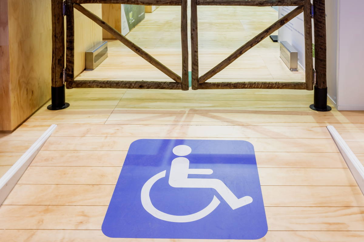 Wheelchair symbol on the floor of a ramp leading up to a double swing gate