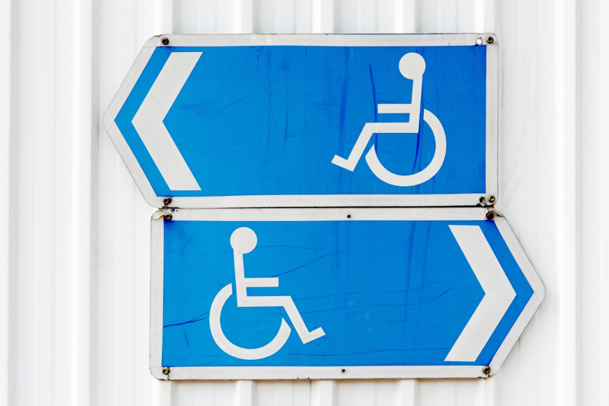 Wheelchair symbols on two arrow-shaped signs pointing in opposite direction