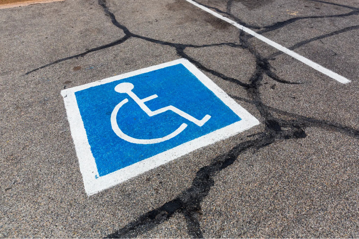 Wheelchair symbol painted onto cracked pavement marking accessible parking space