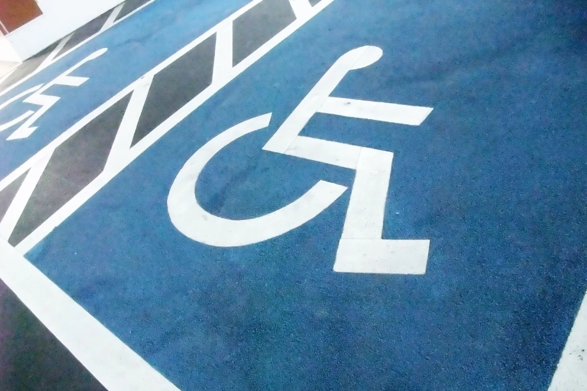 Closeup photo of two accessible parking spaces side by side, with access asiles, marked by blue and white wheelchair symbols