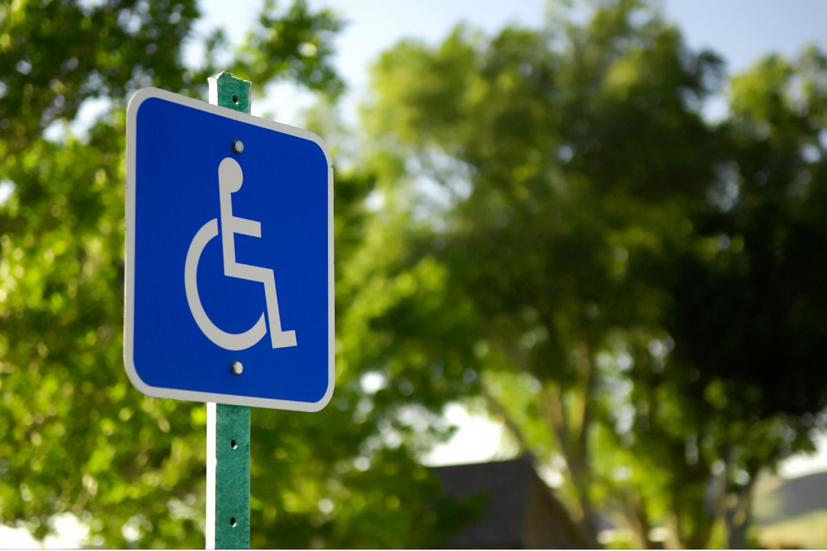 Wheelchair symbol sign with green trees in the background