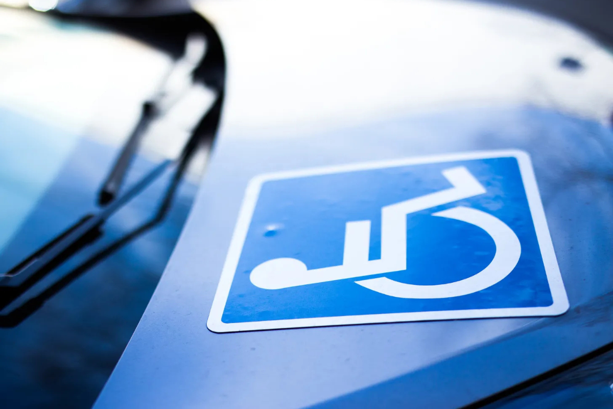 White on blue wheelchair symbol stuck on the hood of a blue c