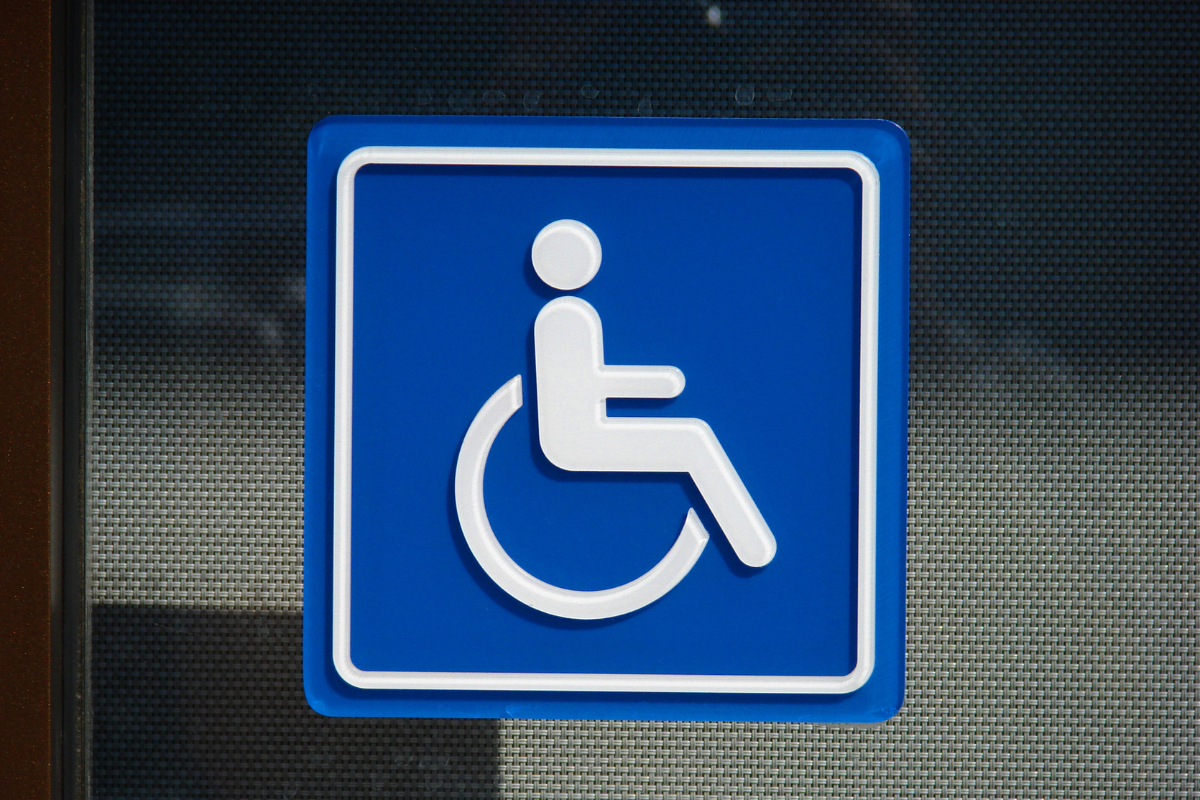 White on blue wheelchair sumbol sign posted on a dark surface