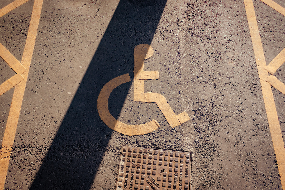 Yellow wheelchair symbol painted onto rough pavement marking an accessible parking space