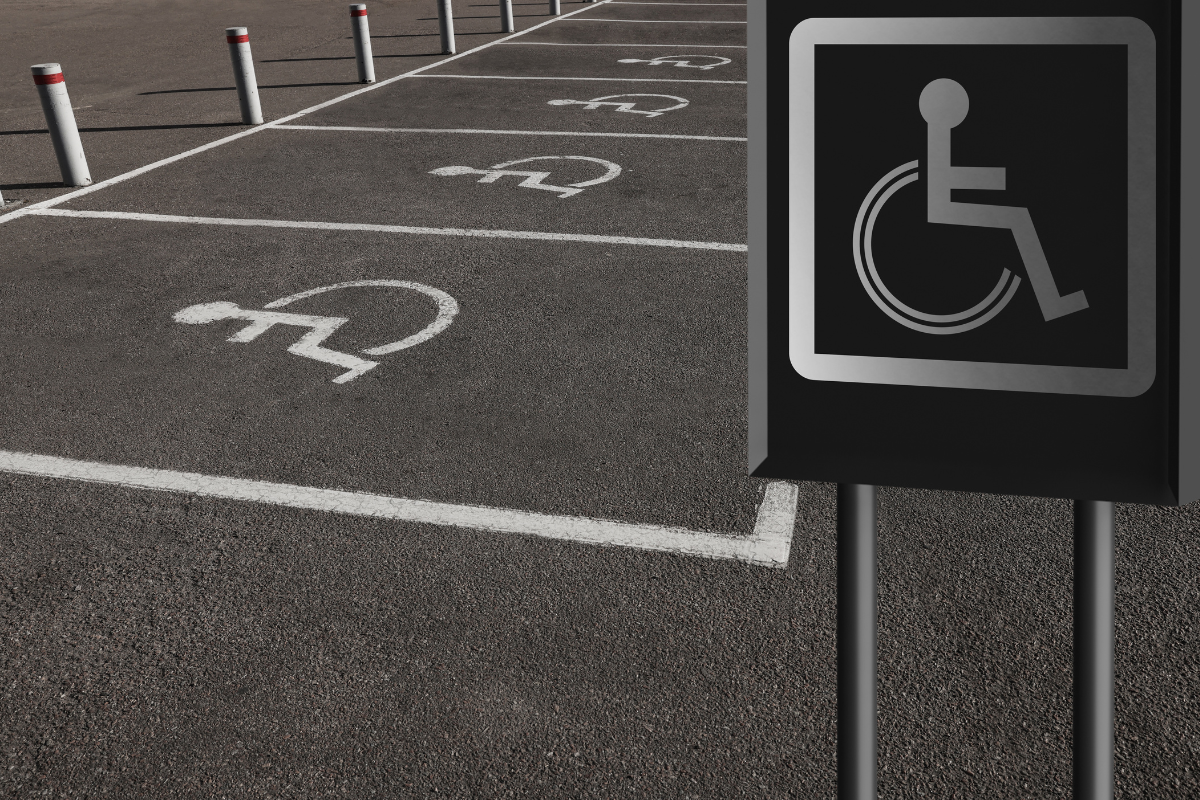 Four accessible parking spaces marked on pavement and by a white on black wheelchair sig