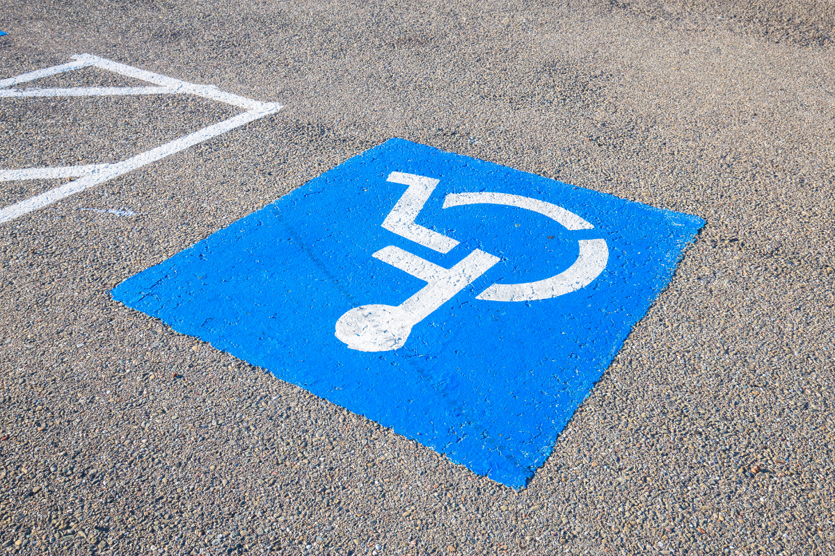 White on blue wheelchair symbol painted on pavement to mark accessible parking space