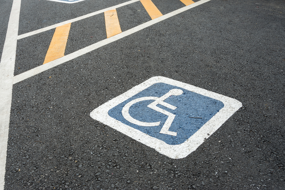 Accessible parking space marked by white on blue wheelchair symbol on black pavement
