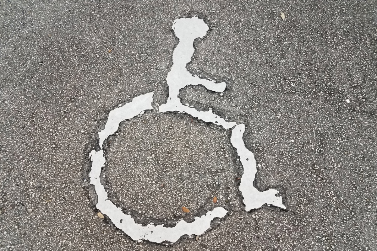 Ragged, worn away white wheelchar symbol painted into pavement