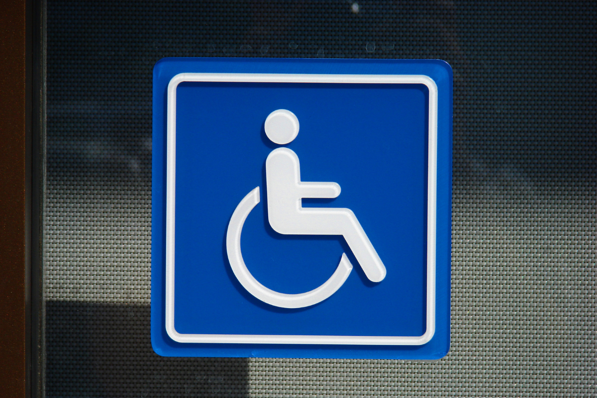 White on blue wheelchair symbol sign posted on a plain dark surface
