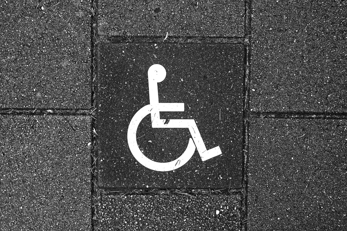 White wheelchair symbol stenciled on a wall of dark grey brick