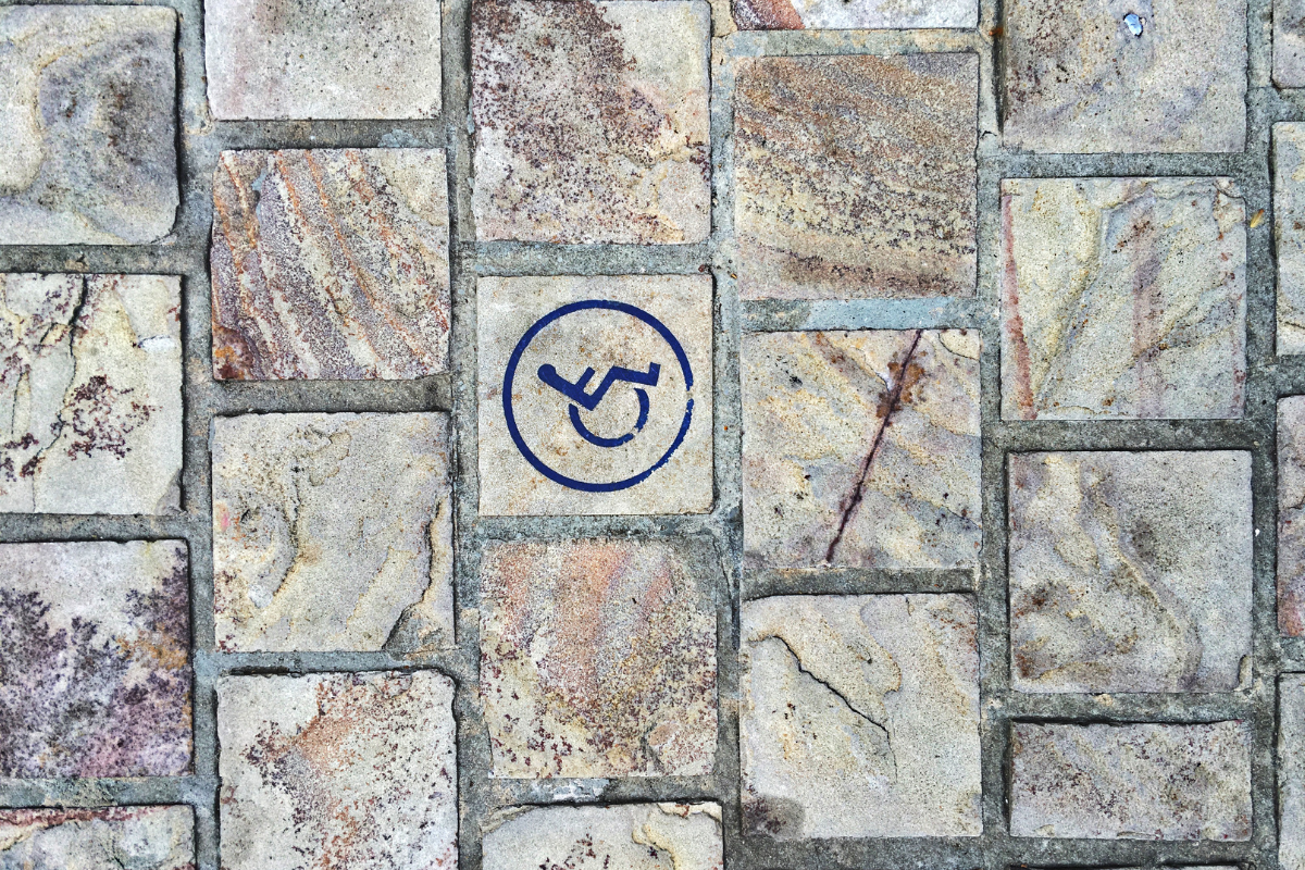 Colorful brick pavement with blue wheelchair symbol stenciled on one brick
