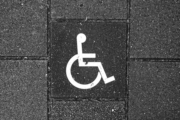 White wheelchair symbol embossed on dark grey brick wall