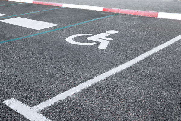 Accessible parking space marked with white lines and a white wheelchair symbol on the paveme