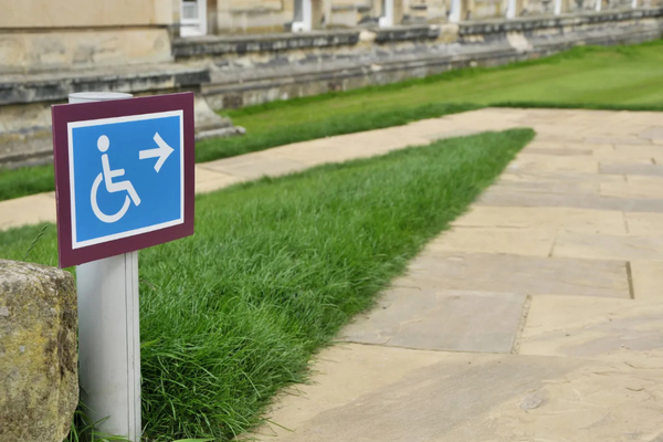 Wheelchair symbol directional sign pointing the way to an accessible outdoor pathway