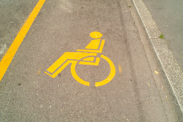 Yellow wheelchair symbol stenciled onto the pavement of a parking spa