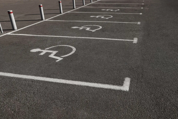 A row of accessible parking spaces marked n black pavement with white lines and wheelchair symbols