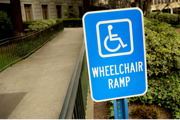 White on blue wheelchair symbol sign labeled "Wheelchair Ramp", next to a long outdoor ramp