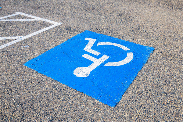 White on blue wheelchair symbol painted on pavement to mark accessible parking space