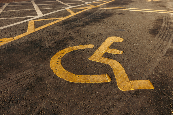 Yellow wheelchair symbol stenciled on pavement marking accessible parking space