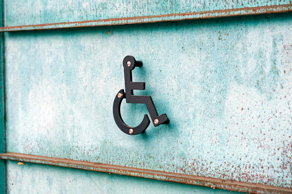 Black metal wheelchair symbol mounted on a blue-green metal wall