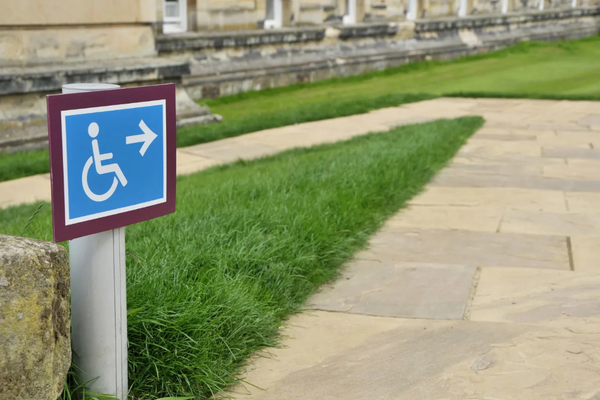 Accessible sidewalk and ramp path marked with a white on blue wheelchair symbol sign