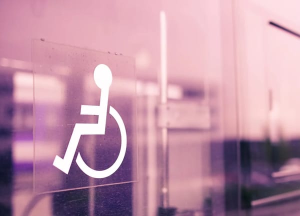 White wheelchair symbol decal on an pink-tinted glass wall