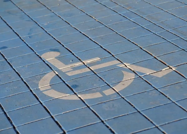 A white wheelchair symbol stenciled on light blue tiles