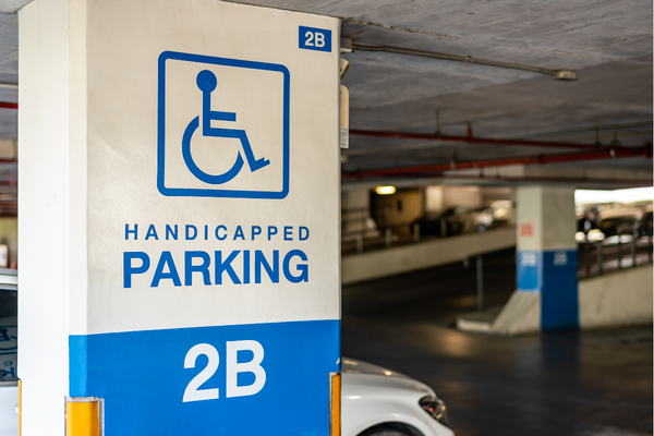 Blue on white wheelchair symbol marking a "Handicapped Parking" area of an indoor parking garage