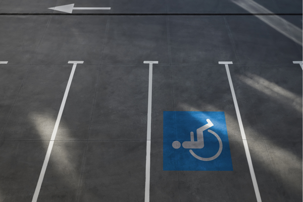 Parking spaces viewed from above, with one marked by white on blue painted wheelchair symbol