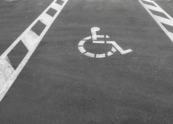 White stenciled wheelchair symbol and lines marking accessible parking space