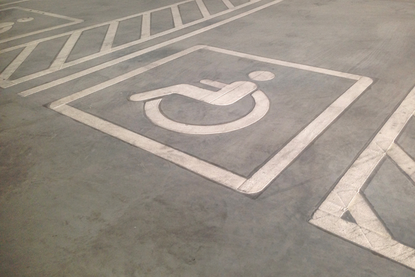 White wheelchair symbol and lines on grey pavement marking accessible parking space
