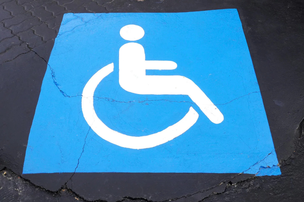 White on blue wheelchair symbol on black pavement