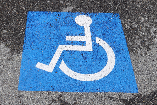 White on blue wheelchair symbol painted onto rough pavement