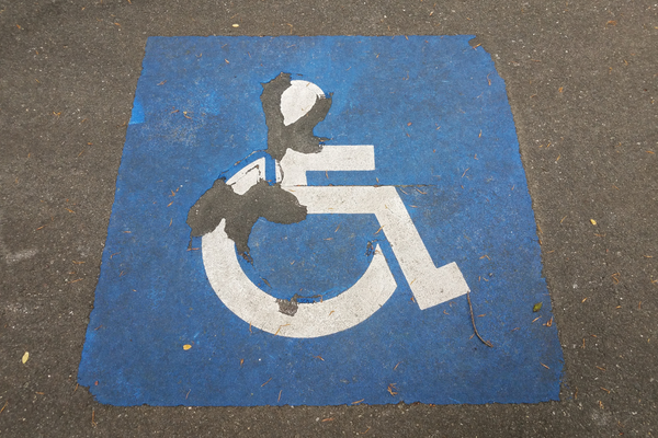 White on blue wheelchair symbol painted on black pavement