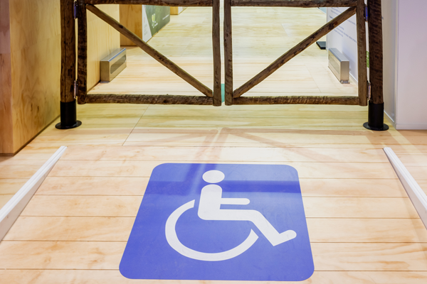White on blue wheelchair symbol on the floor of a ramp leading to an exit gateway