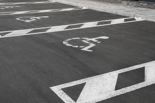 Black & white photo of a row of parking spaces marked with white wheelchair symbols
