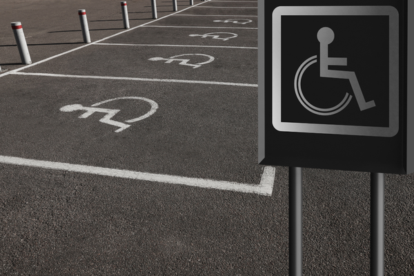 Accessible parking spaces marked with wheelchair symbols on pavement and standing sign
