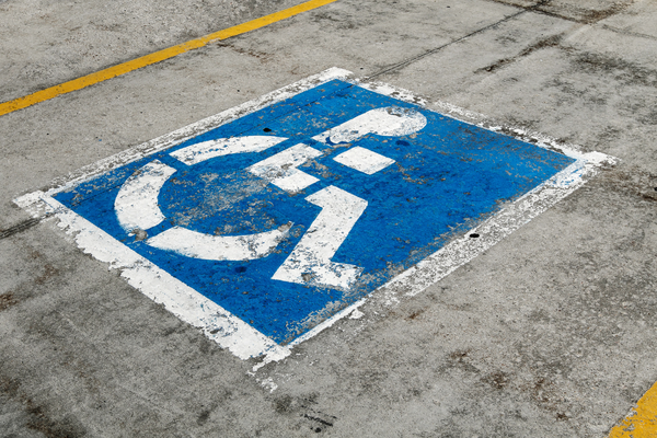 Dirty and peeling white on blue stenciled wheelchair symbol on pavement