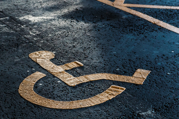 Faded yellow wheelchair symbol on stained blue accessible parking space surface